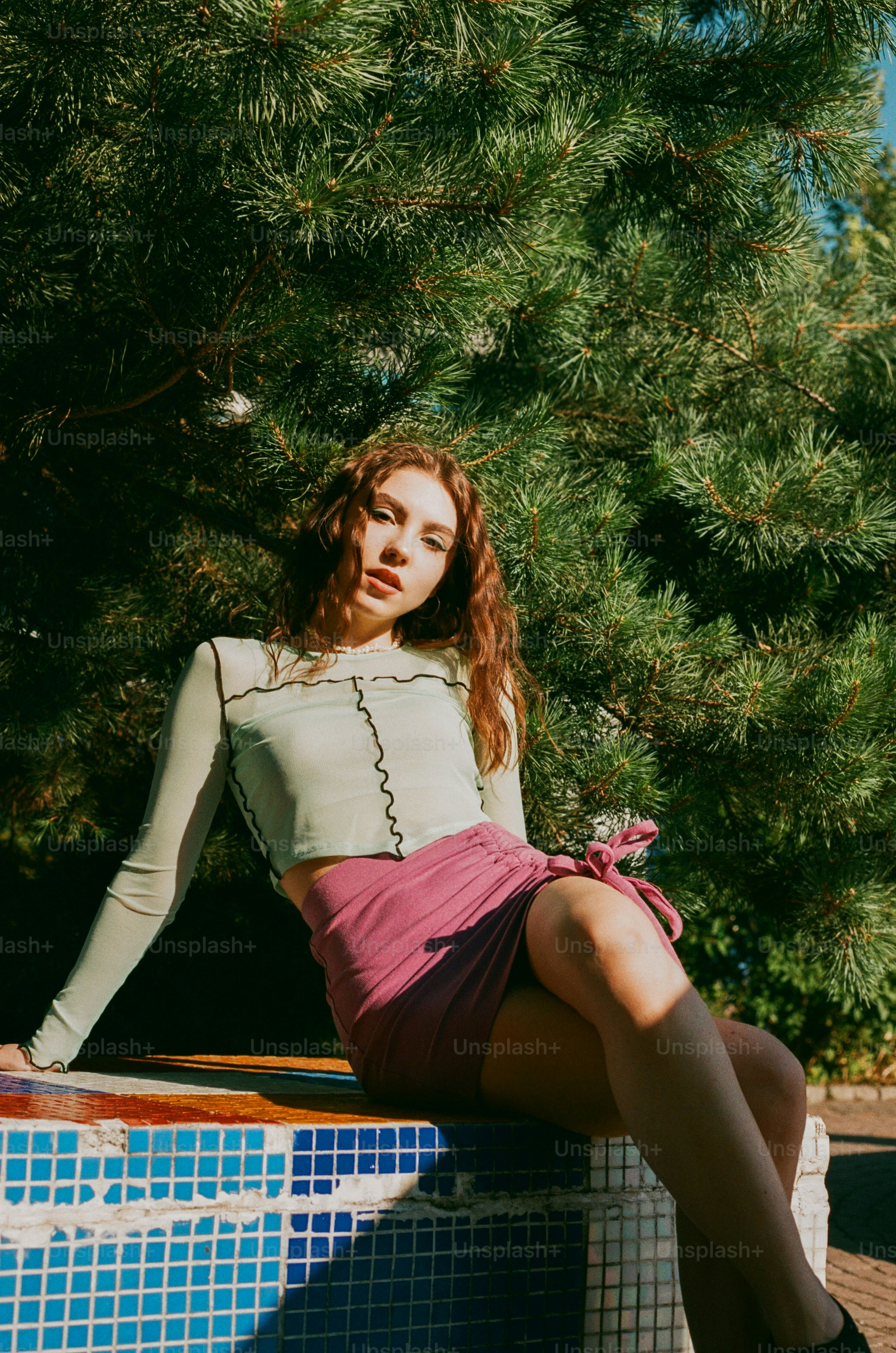 Una donna seduta su una sporgenza vicino a un albero