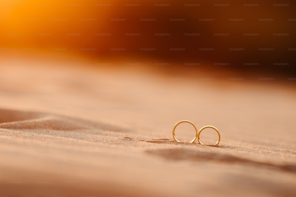 Ein Paar goldene Ohrringe, die auf einem Sandstrand sitzen