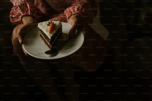 una persona che tiene un piatto con un pezzo di torta su di esso