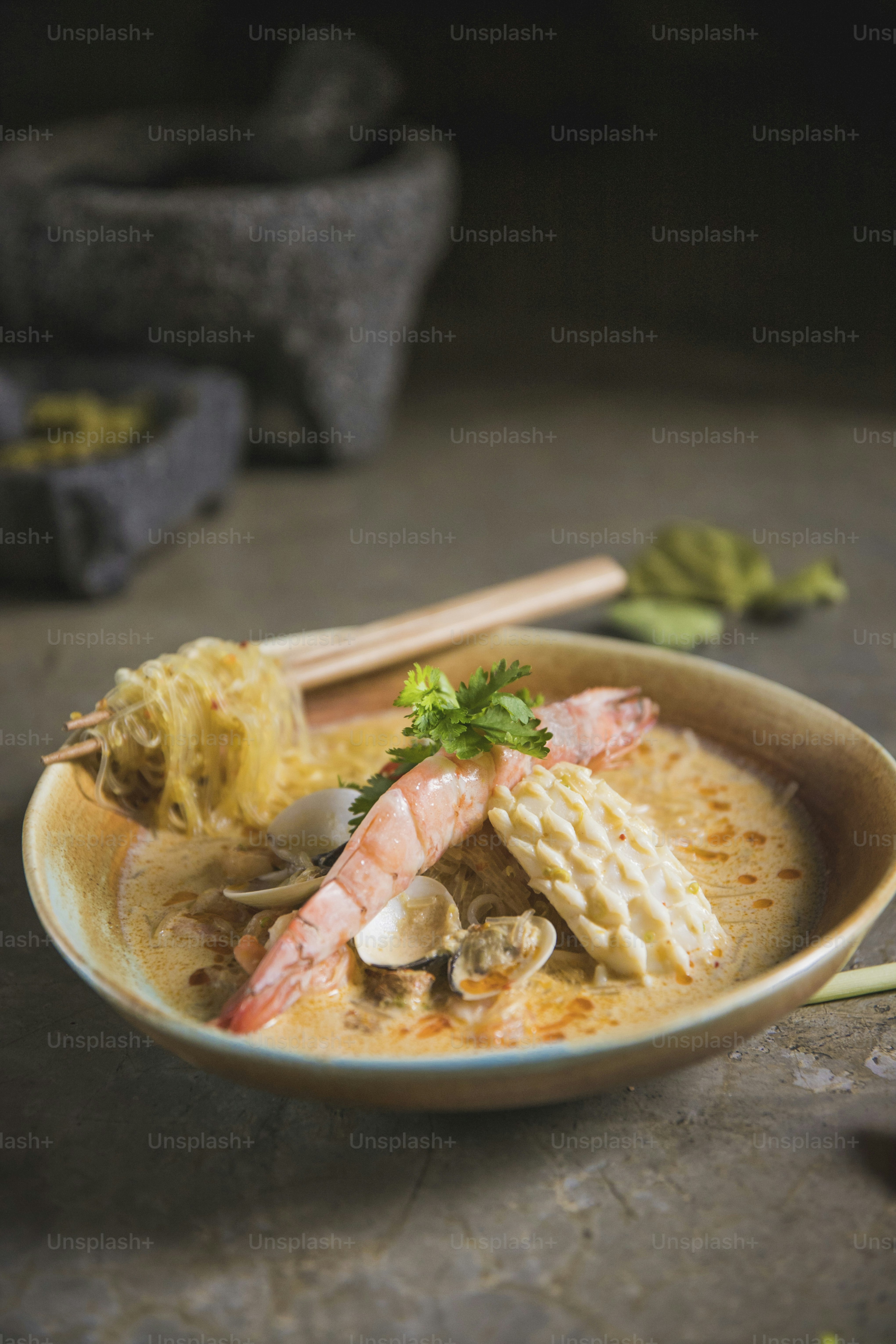uma tigela de sopa com camarão, cogumelos e macarrão