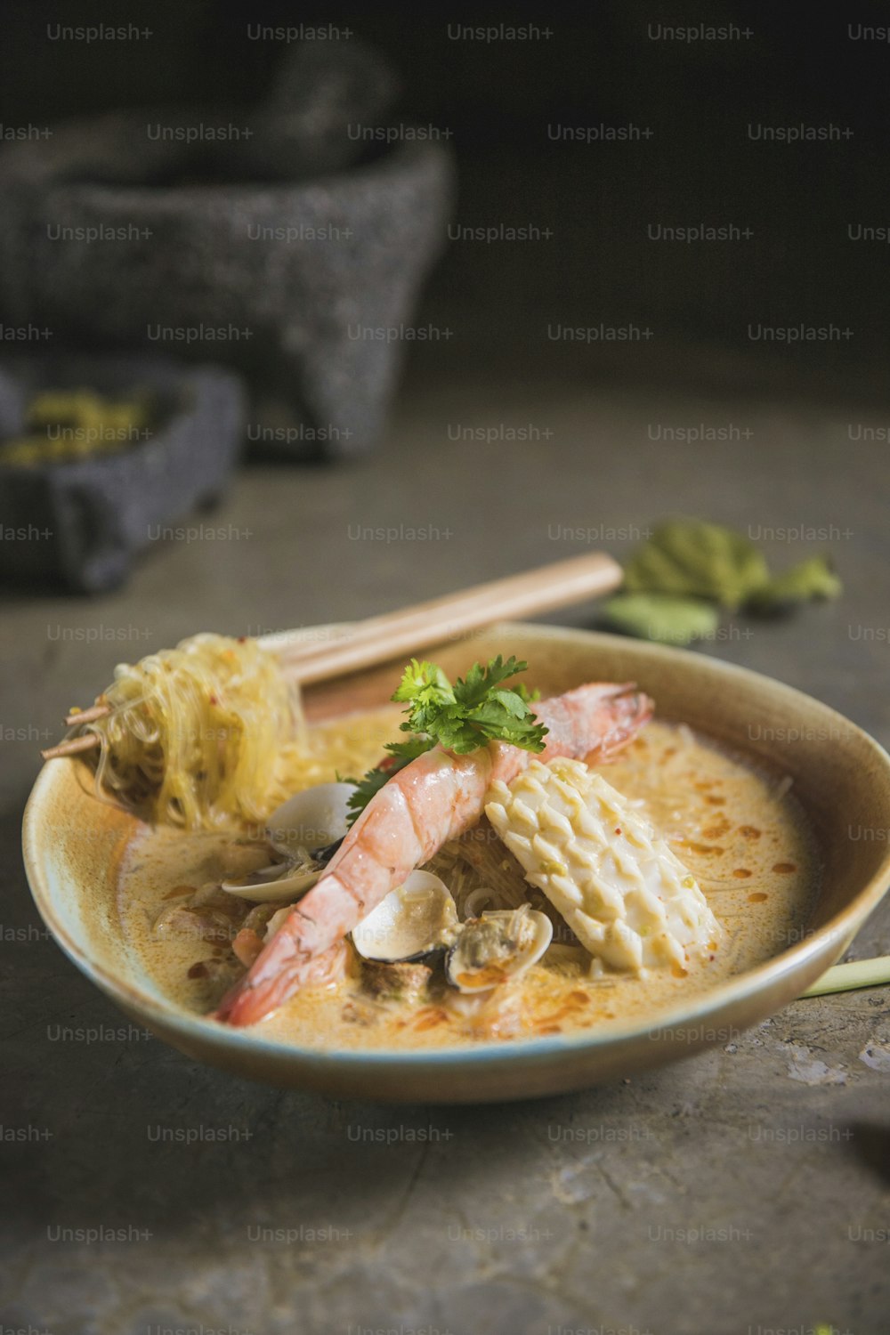 a bowl of soup with shrimp, mushrooms, and noodles