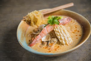 uma tigela de sopa com camarão, camarão e macarrão