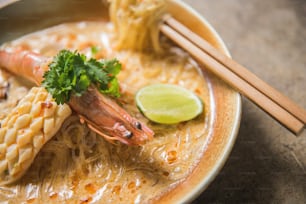 un bol de soupe avec des crevettes et des nouilles