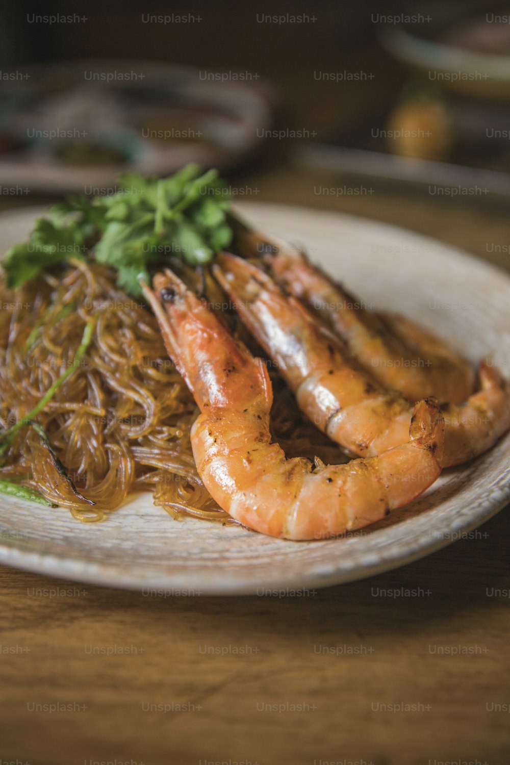 a plate of shrimp and noodles on a wooden table