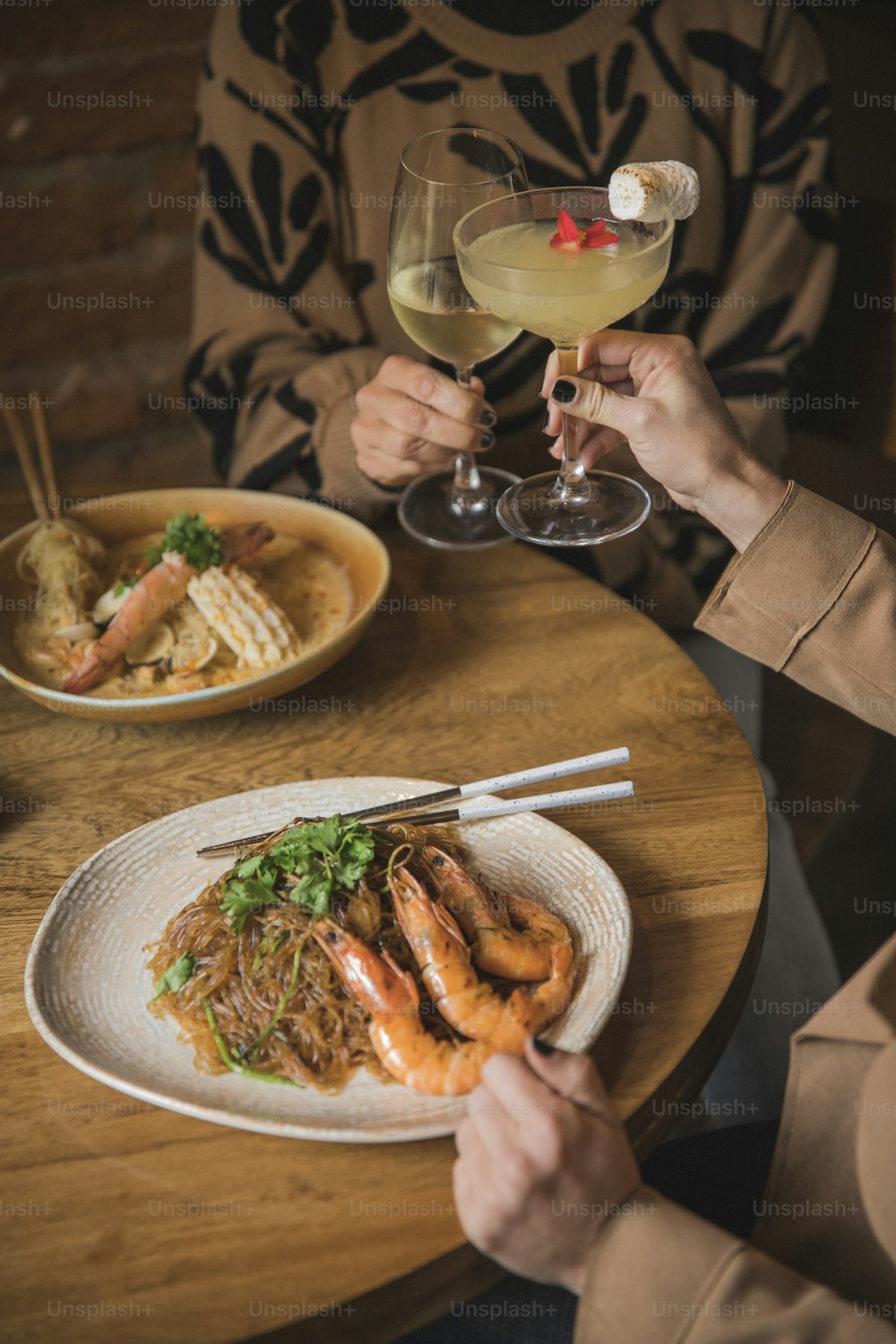 Una persona sentada en una mesa con un plato de comida y una copa de vino