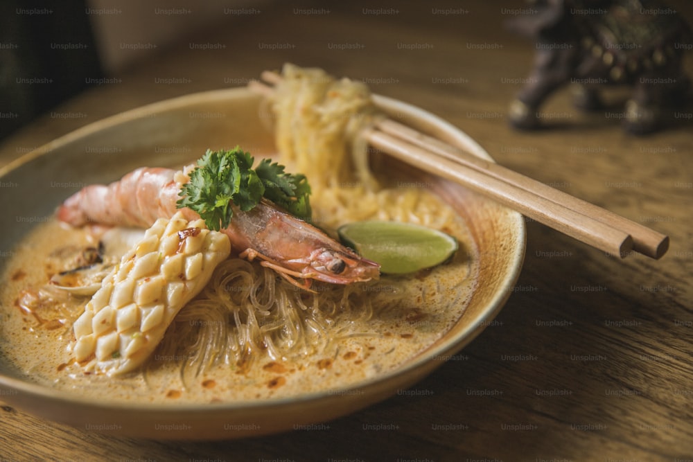 un bol de nouilles et de crevettes avec baguettes