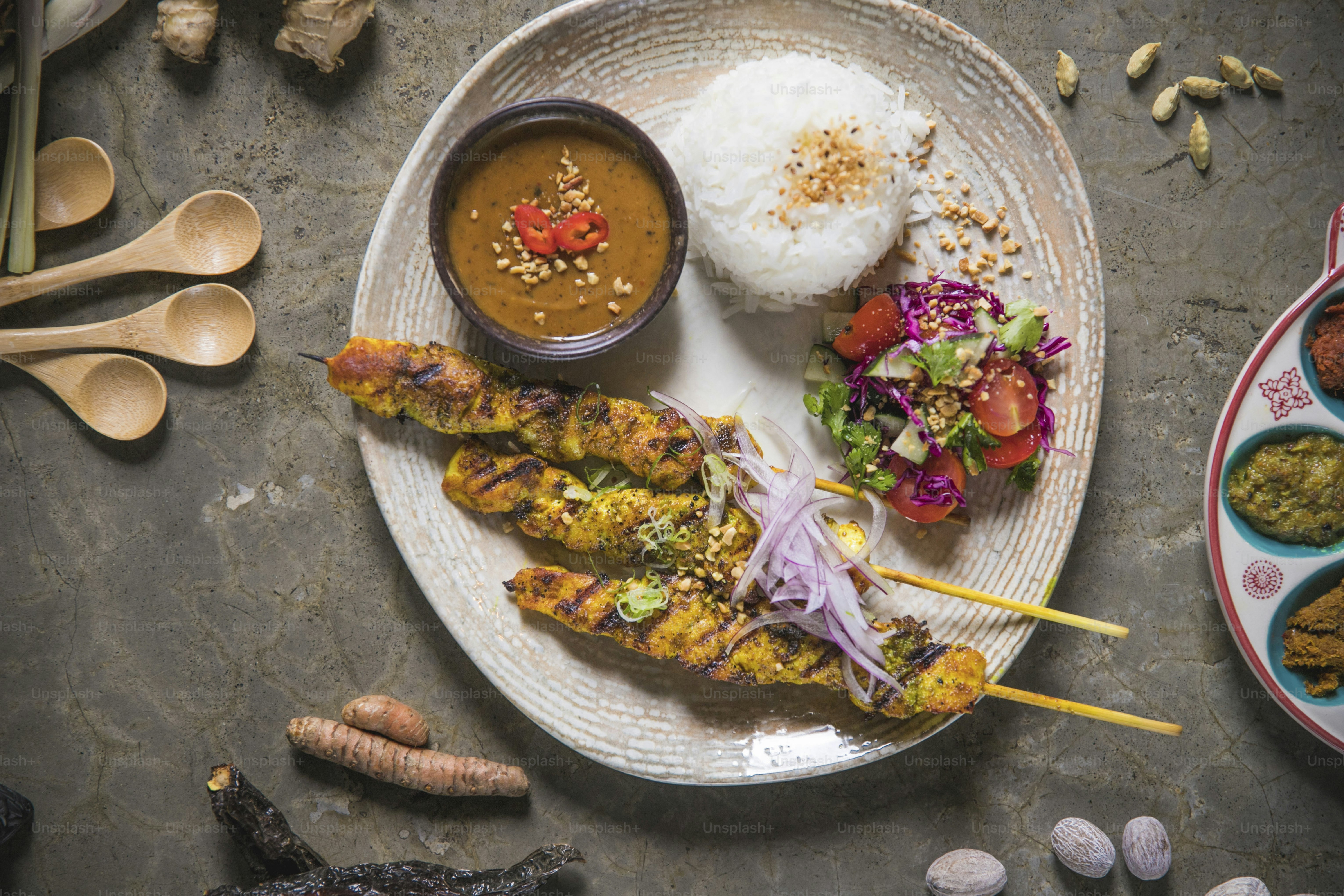 a white plate topped with food next to a bowl of rice
