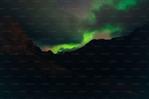 a green and purple aurora over a mountain range