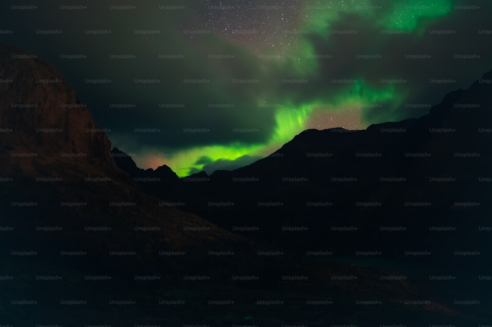 a green and purple aurora over a mountain range