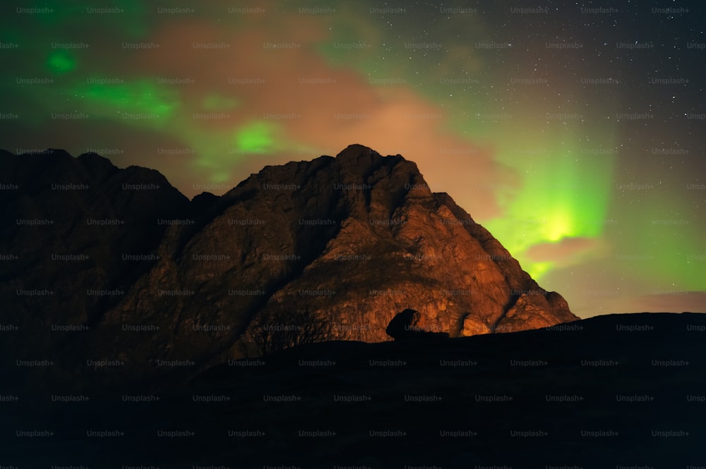 Una persona sentada en la cima de una montaña bajo una luz verde