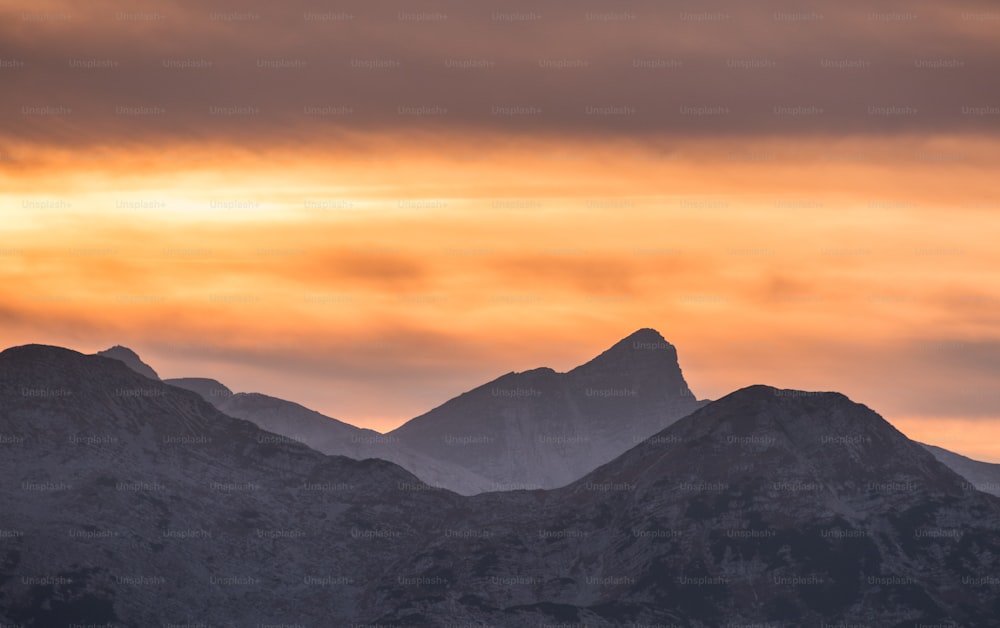 a group of mountains in the distance under a cloudy sky