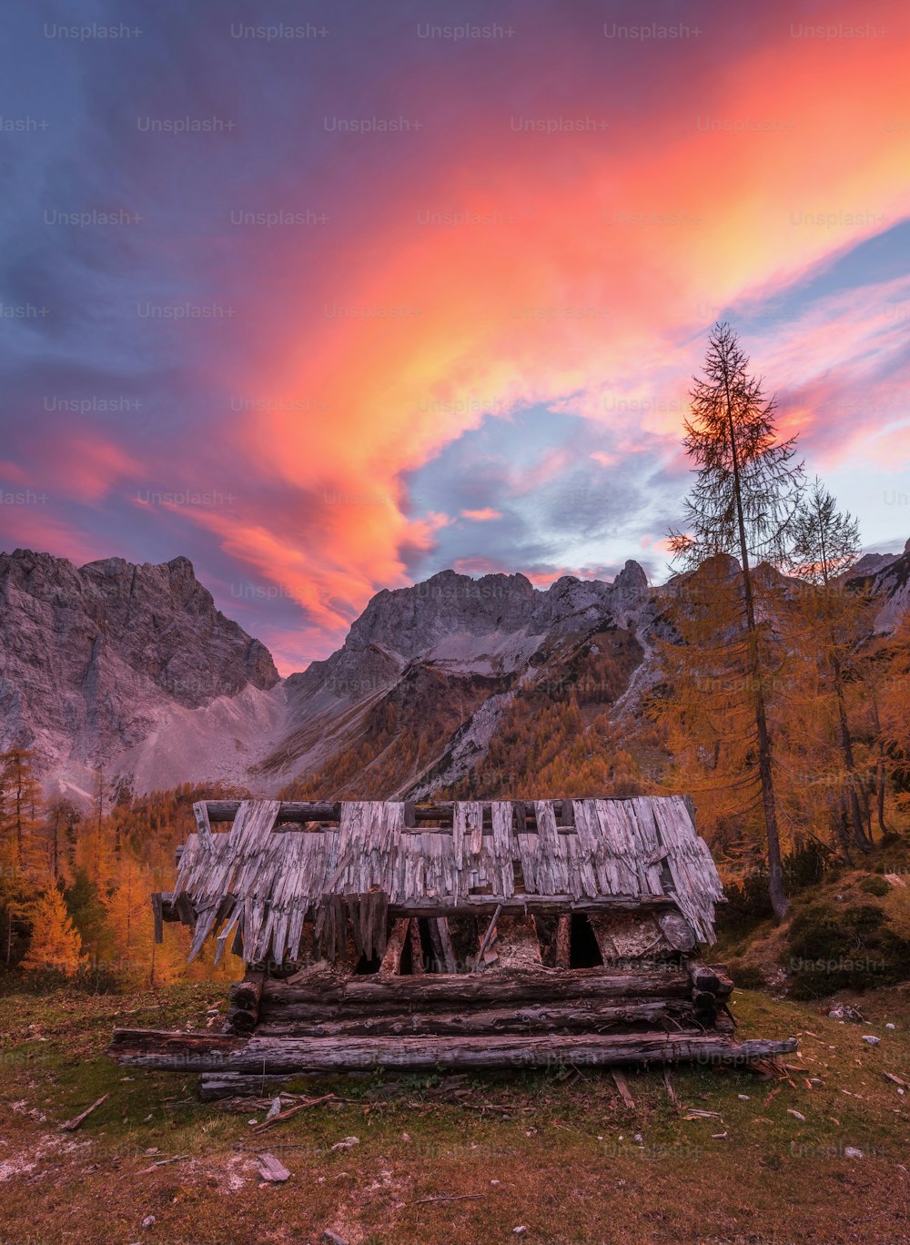 Una cabaña en las montañas con una puesta de sol al fondo