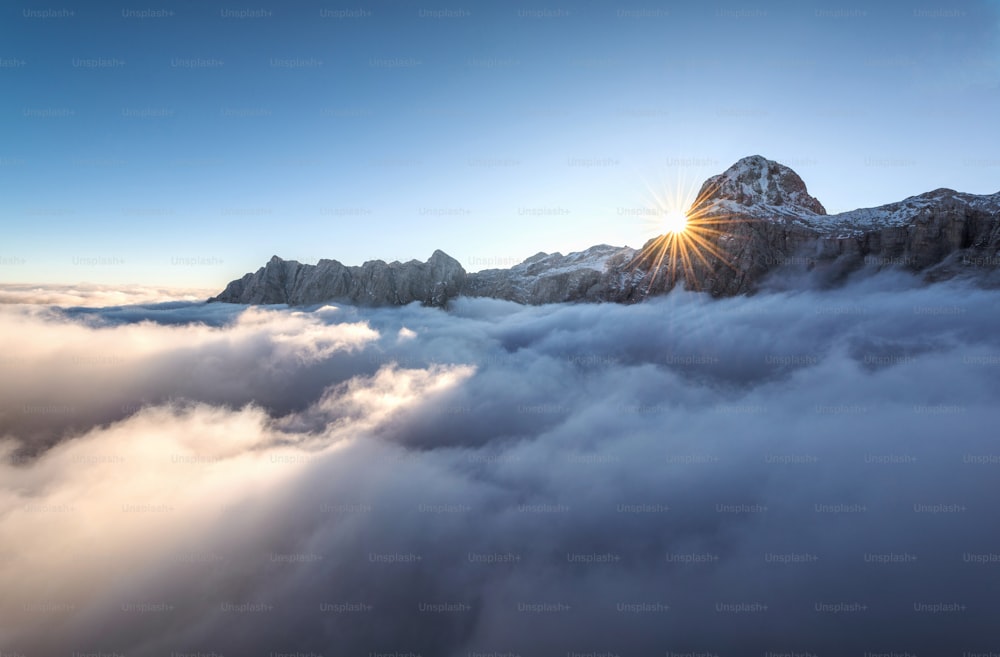 the sun shines brightly above the clouds in the mountains