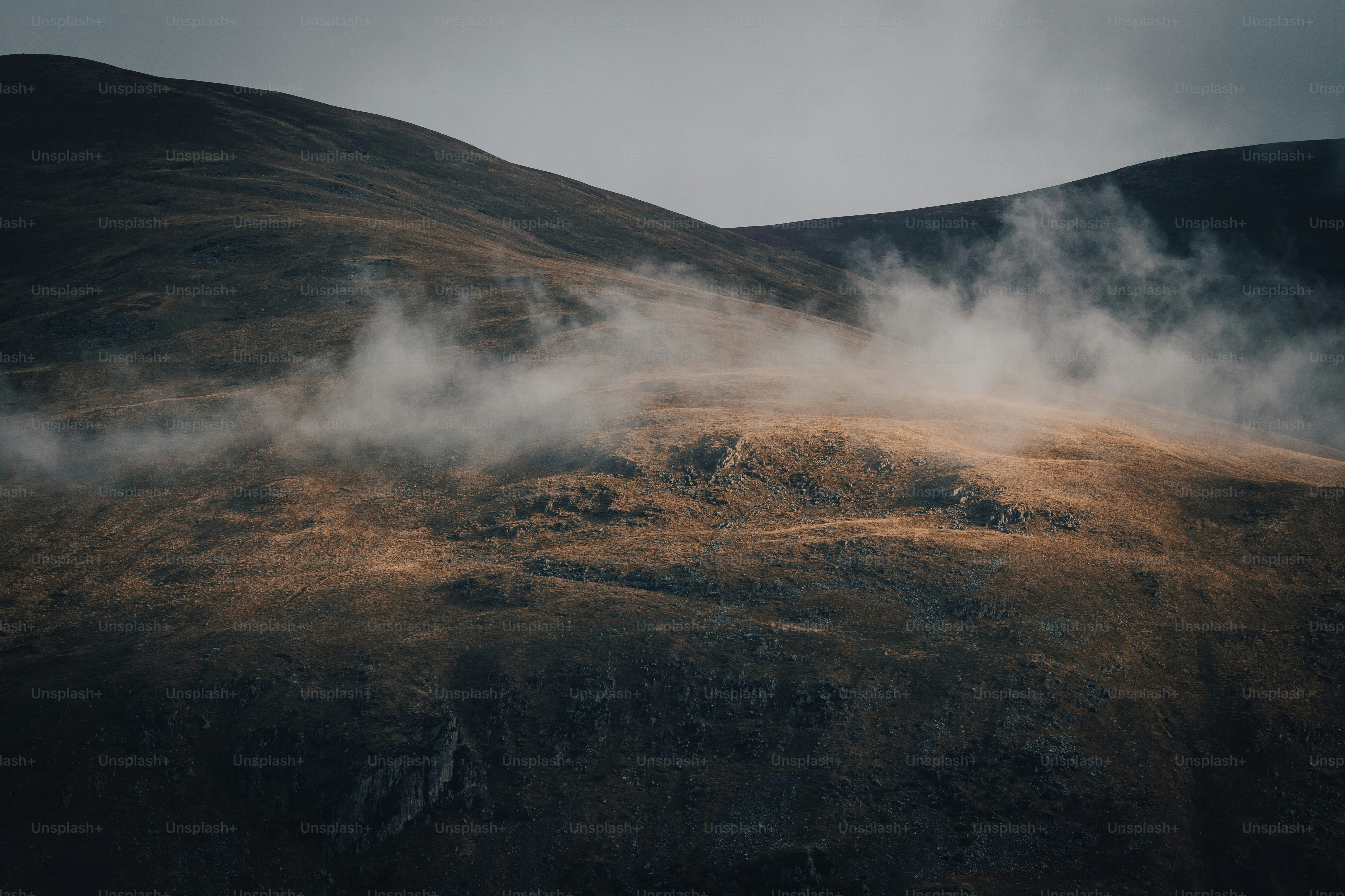 a hill covered in fog and clouds on a cloudy day