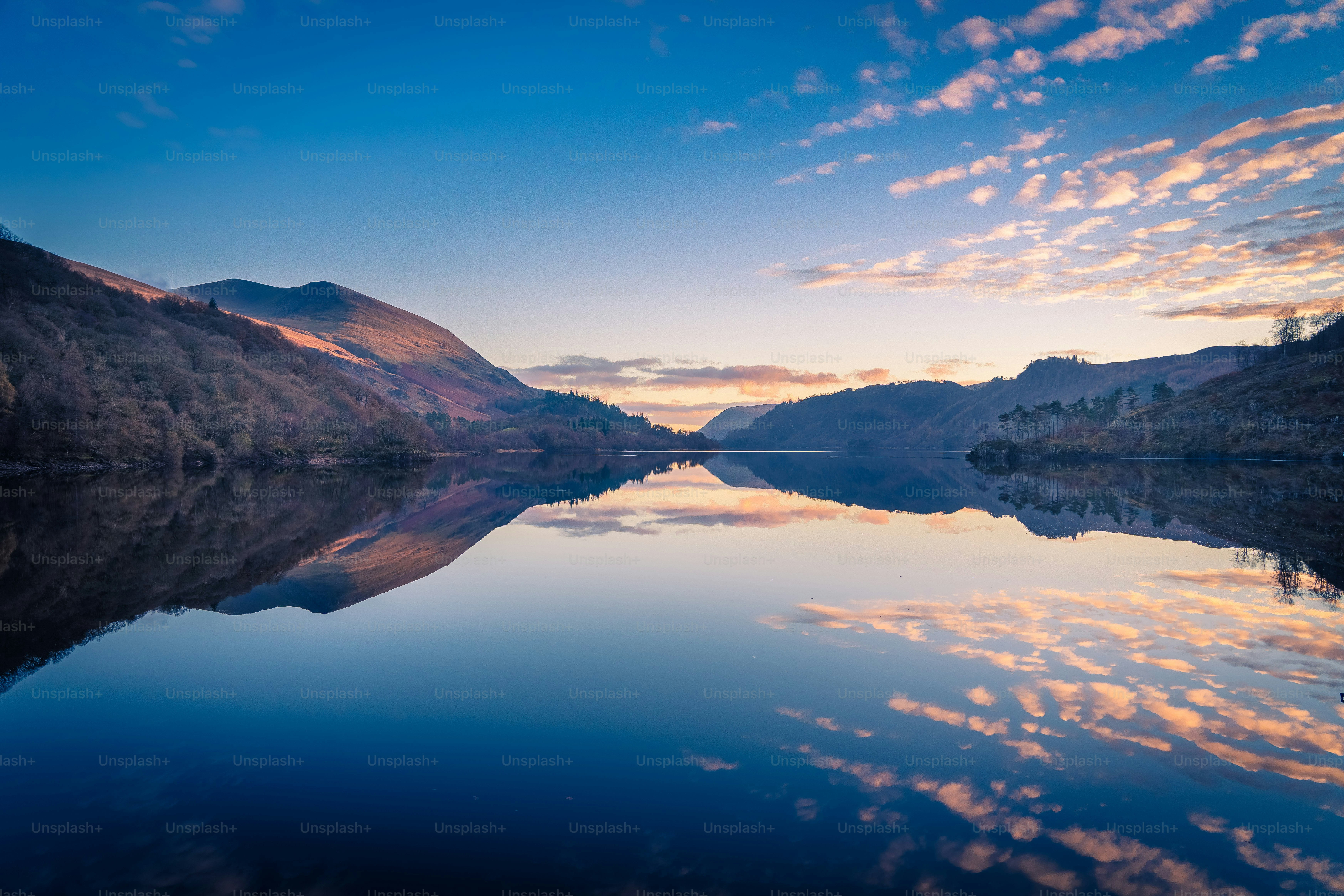 a lake surrounded by mountains under a blue sky