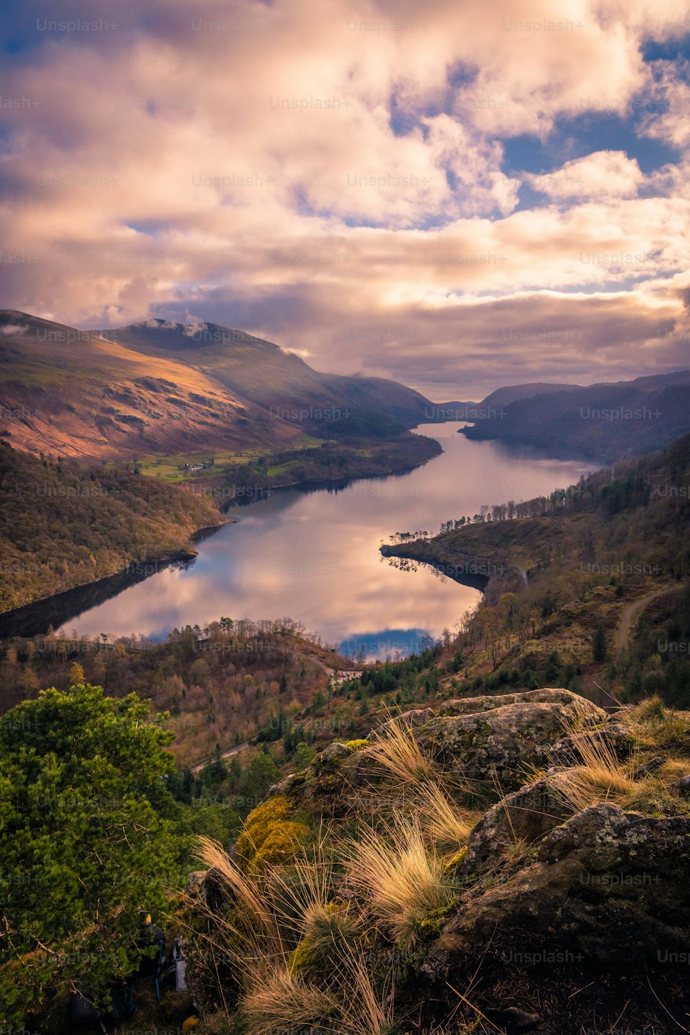 a lake surrounded by mountains under a cloudy sky