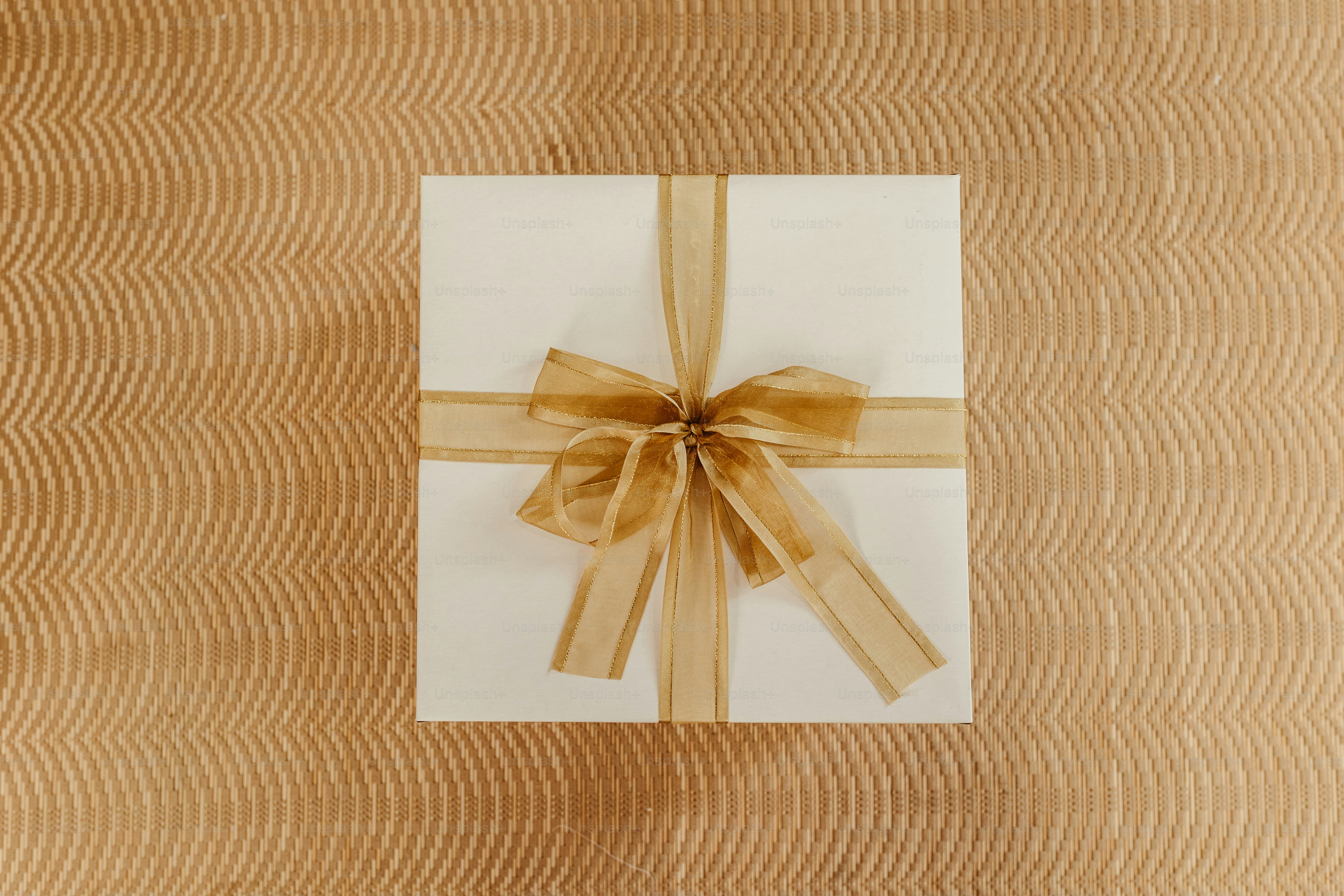 a white gift box with a brown ribbon