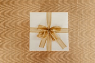 a white gift box with a brown ribbon