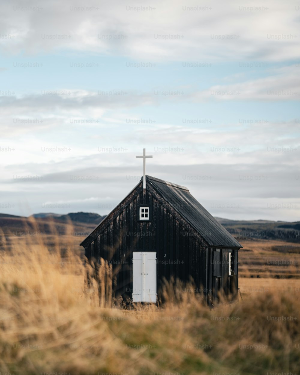 uma pequena igreja preta com uma cruz em cima dela