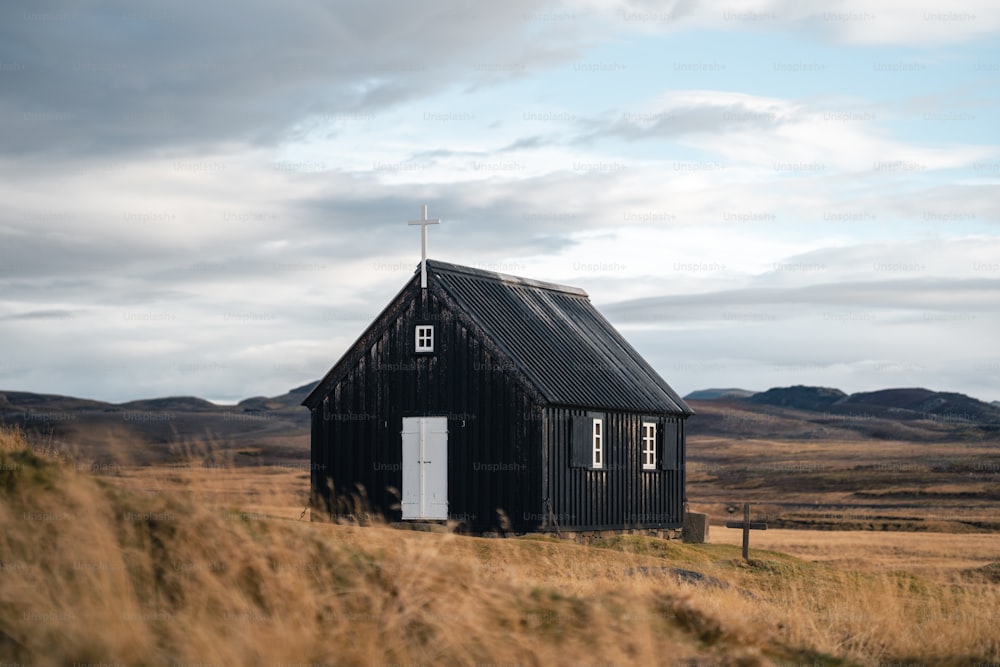 a small black building with a cross on top of it