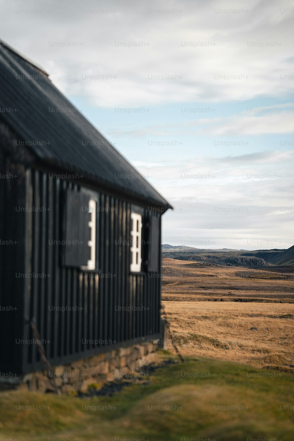 a black building sitting in the middle of a field