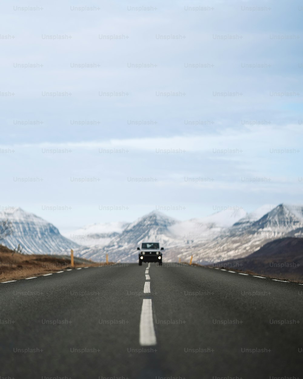 a car driving down a road with mountains in the background