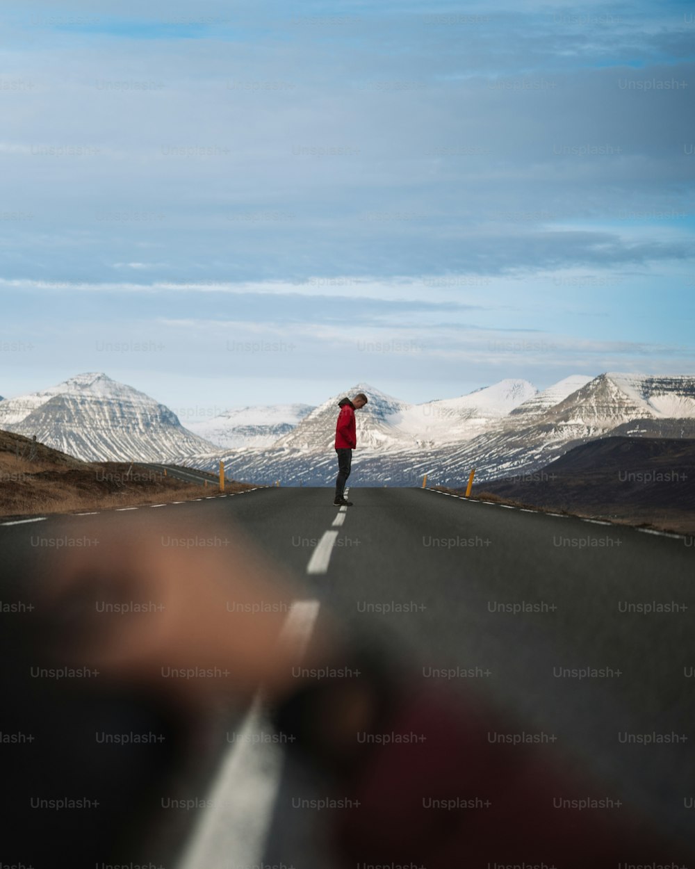 Eine Person, die auf einer Straße mit schneebedeckten Bergen im Hintergrund geht