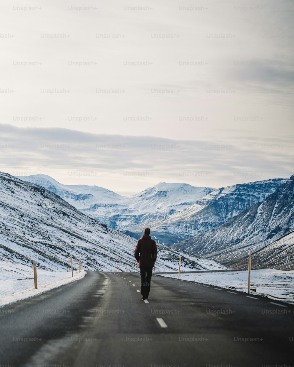 a man walking on a road in the snow