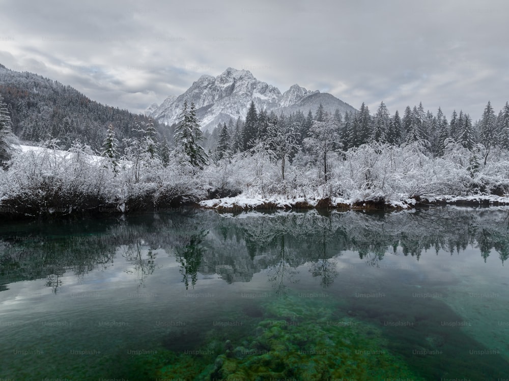 a lake surrounded by snow covered mountains and trees