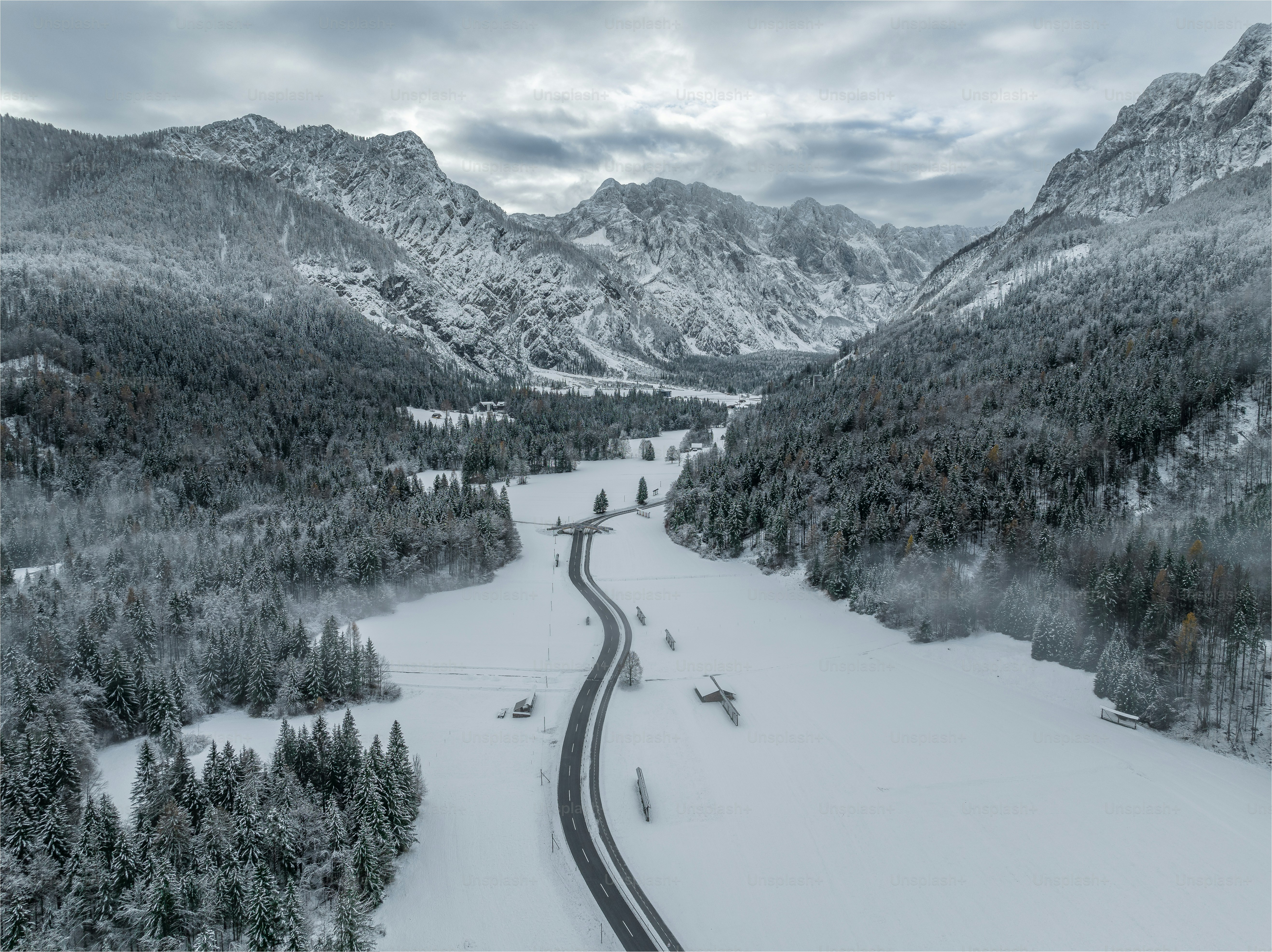 A winding road surrounded by snow covered mountains photo – Winter ...