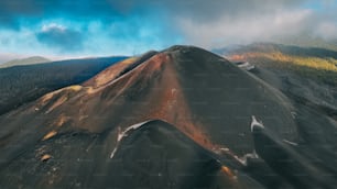 an aerial view of a mountain with a cloudy sky