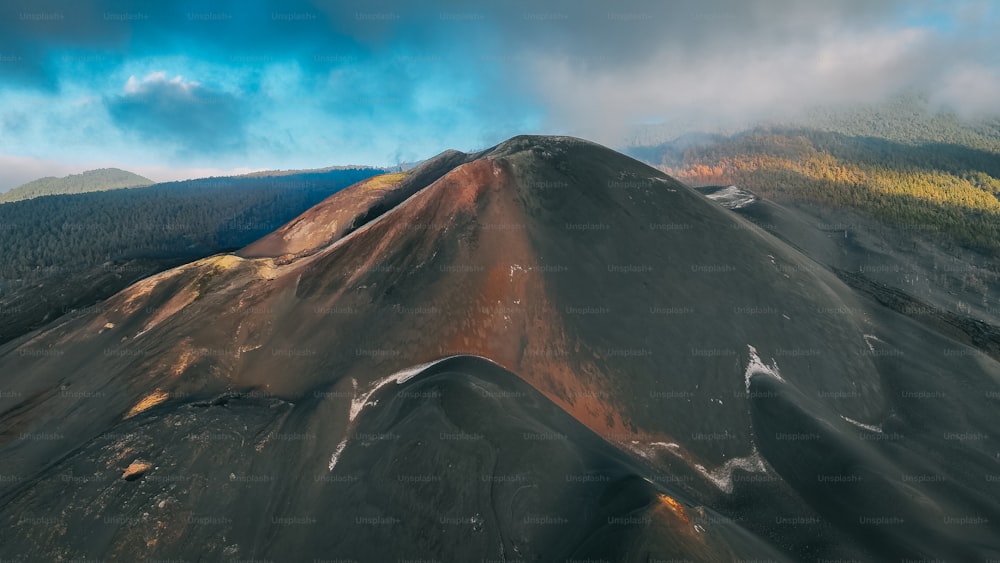 an aerial view of a mountain with a cloudy sky