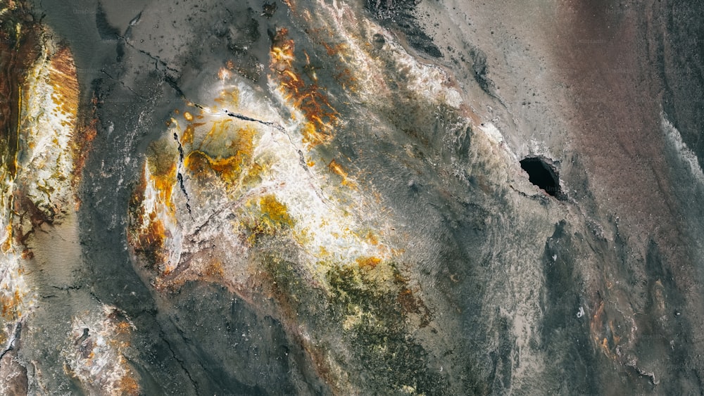 an aerial view of a rock formation with yellow and brown paint