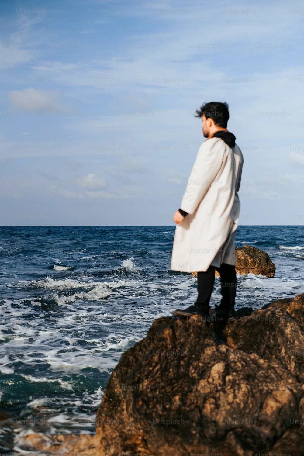 Un uomo in piedi sulla cima di una roccia vicino all'oceano