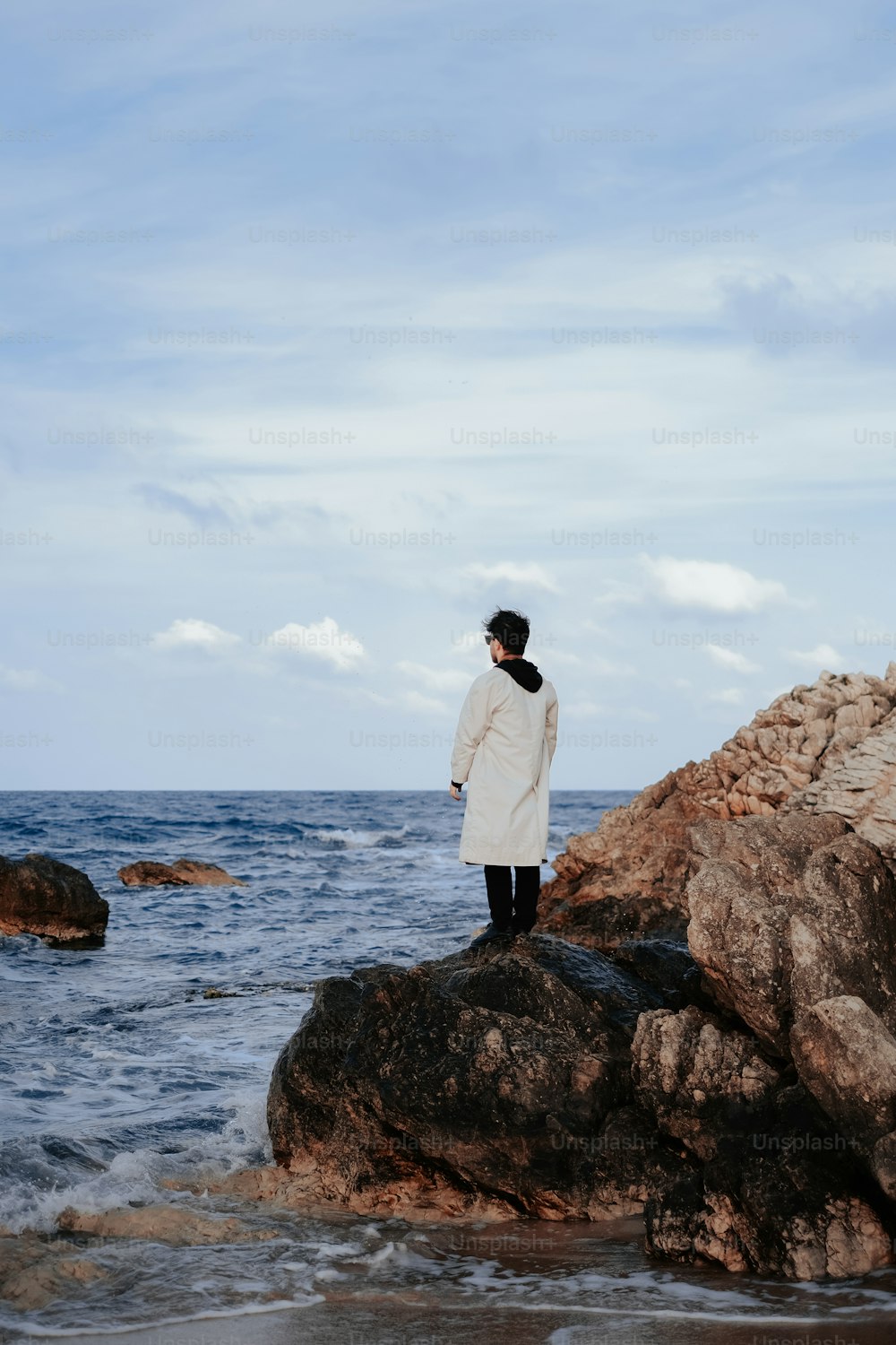 Un uomo in piedi sulla cima di una roccia vicino all'oceano