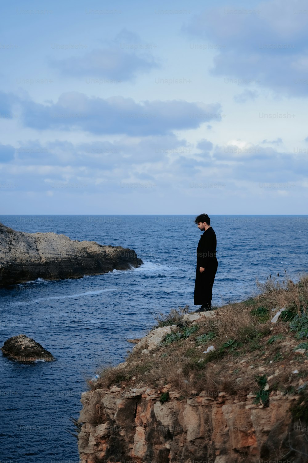 Un uomo in piedi su una scogliera che domina l'oceano