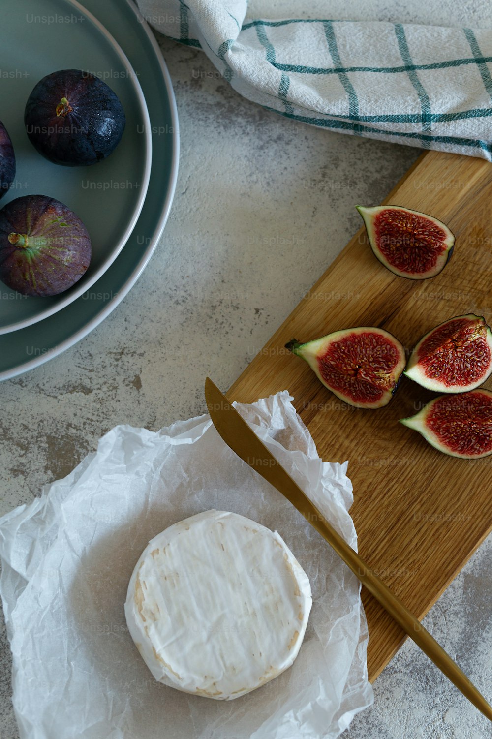 a wooden cutting board topped with cheese and figs