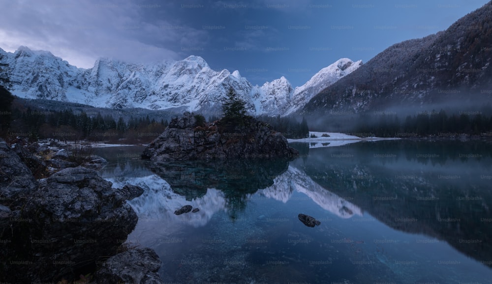 a body of water surrounded by mountains under a cloudy sky