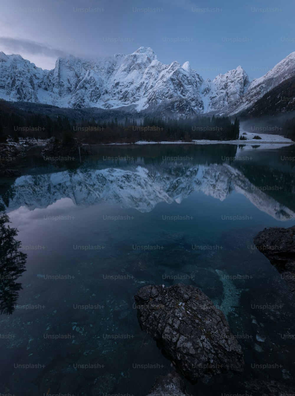 a mountain range is reflected in the still water of a lake