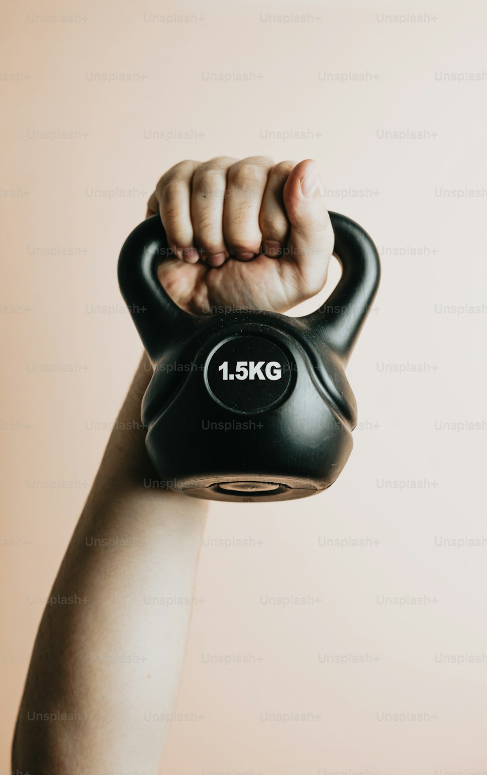 a hand holding a black kettle with the number 1 5kg on it