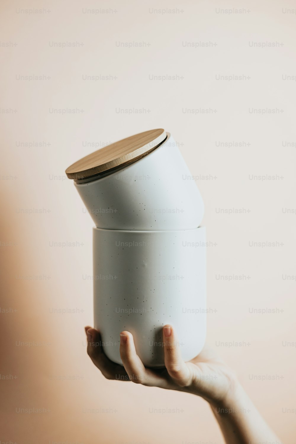 uma pessoa segurando um recipiente branco com uma tampa de madeira