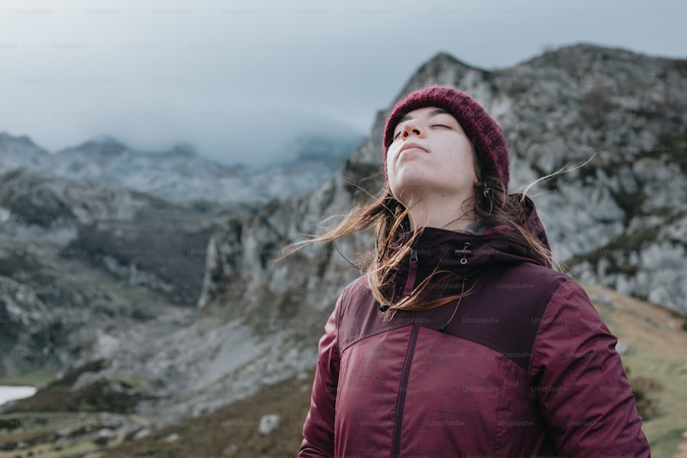 a woman standing on top of a mountain with her eyes closed