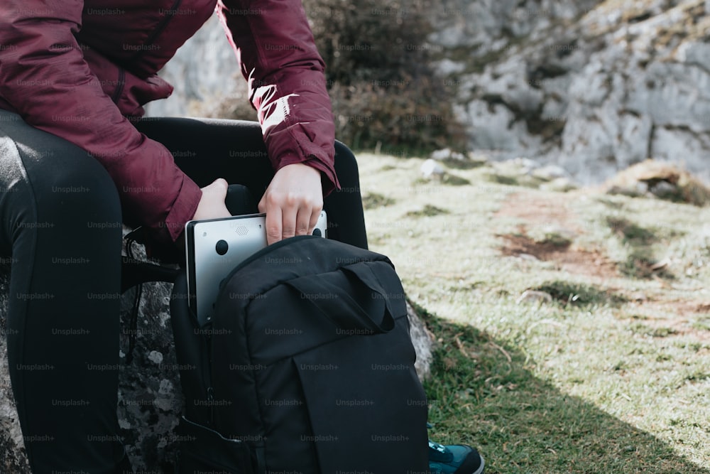 a person sitting on a rock with a backpack