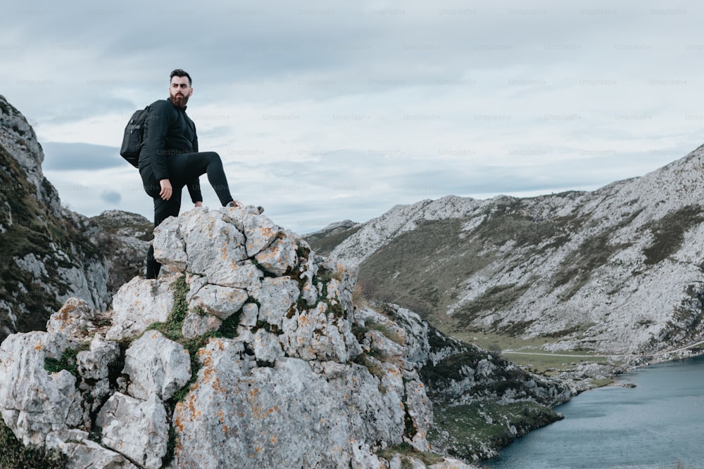 Un uomo seduto sulla cima di una roccia vicino a un lago