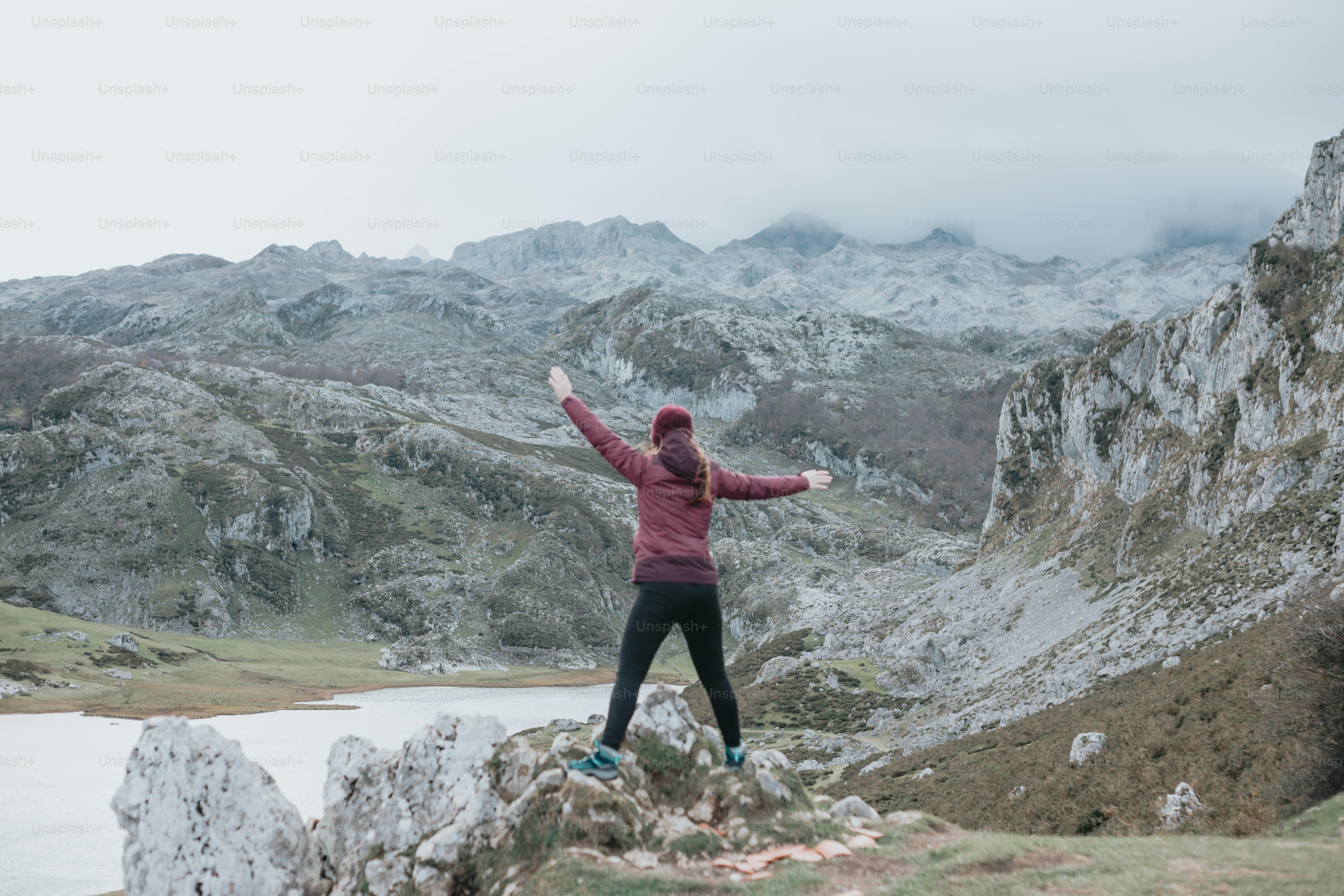 a woman standing on top of a mountain next to a lake