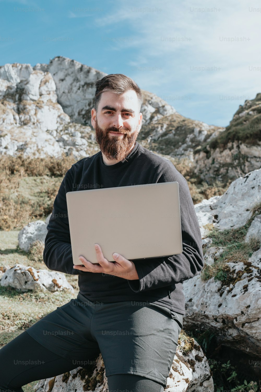 a man sitting on a rock holding a laptop