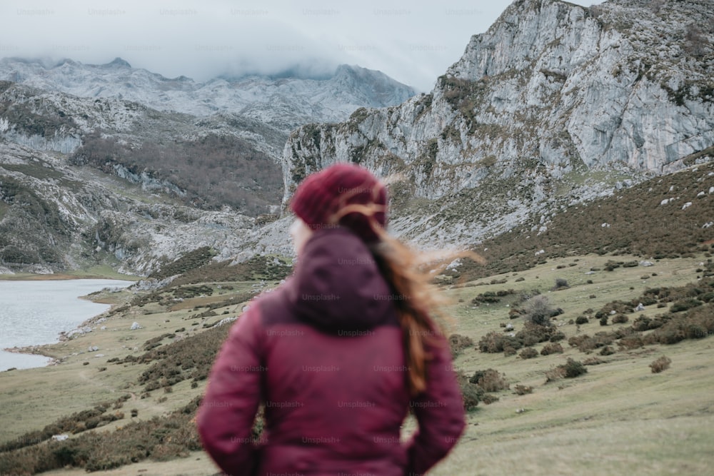 uma mulher em uma jaqueta roxa olhando para uma montanha