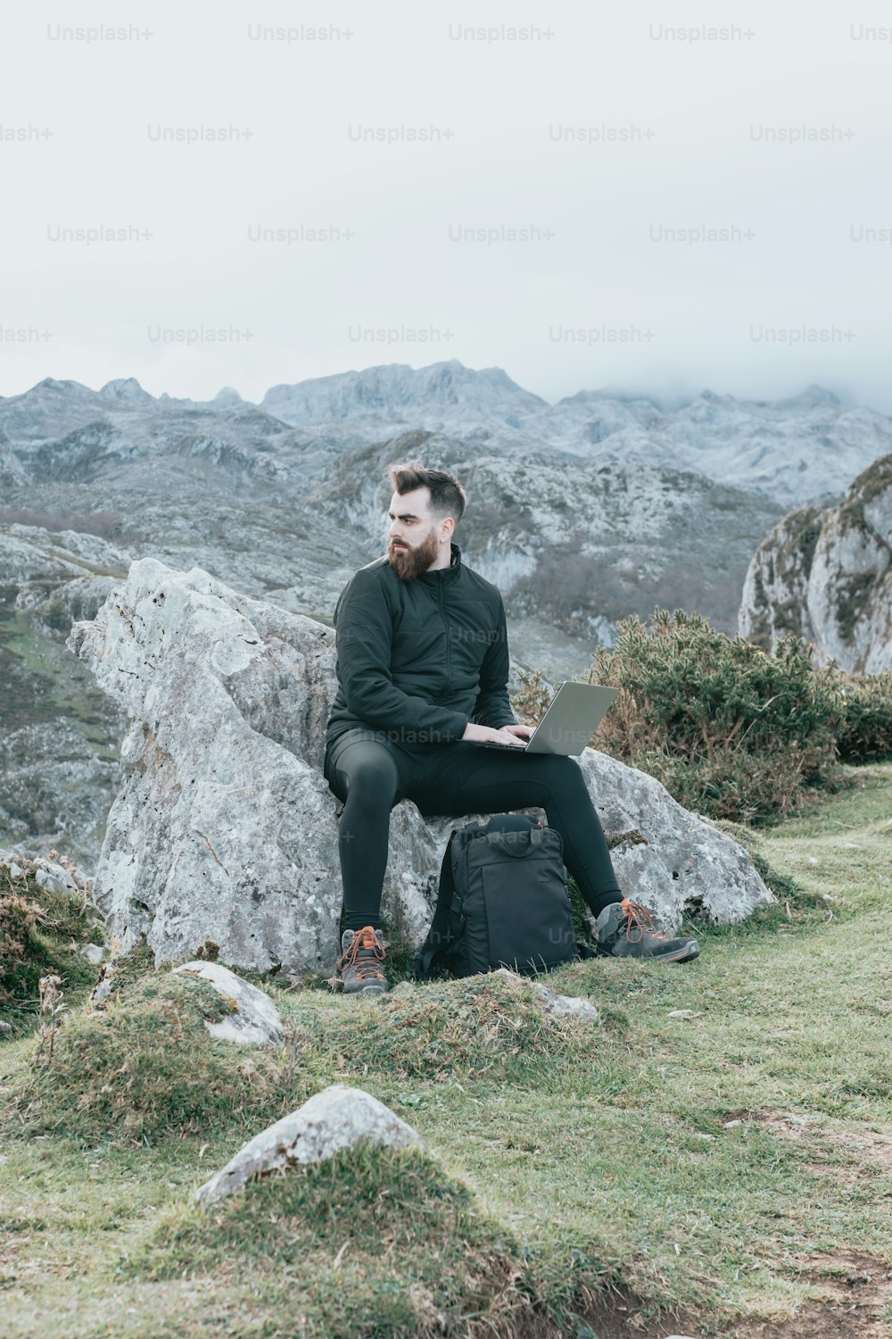 a man sitting on a rock with a backpack