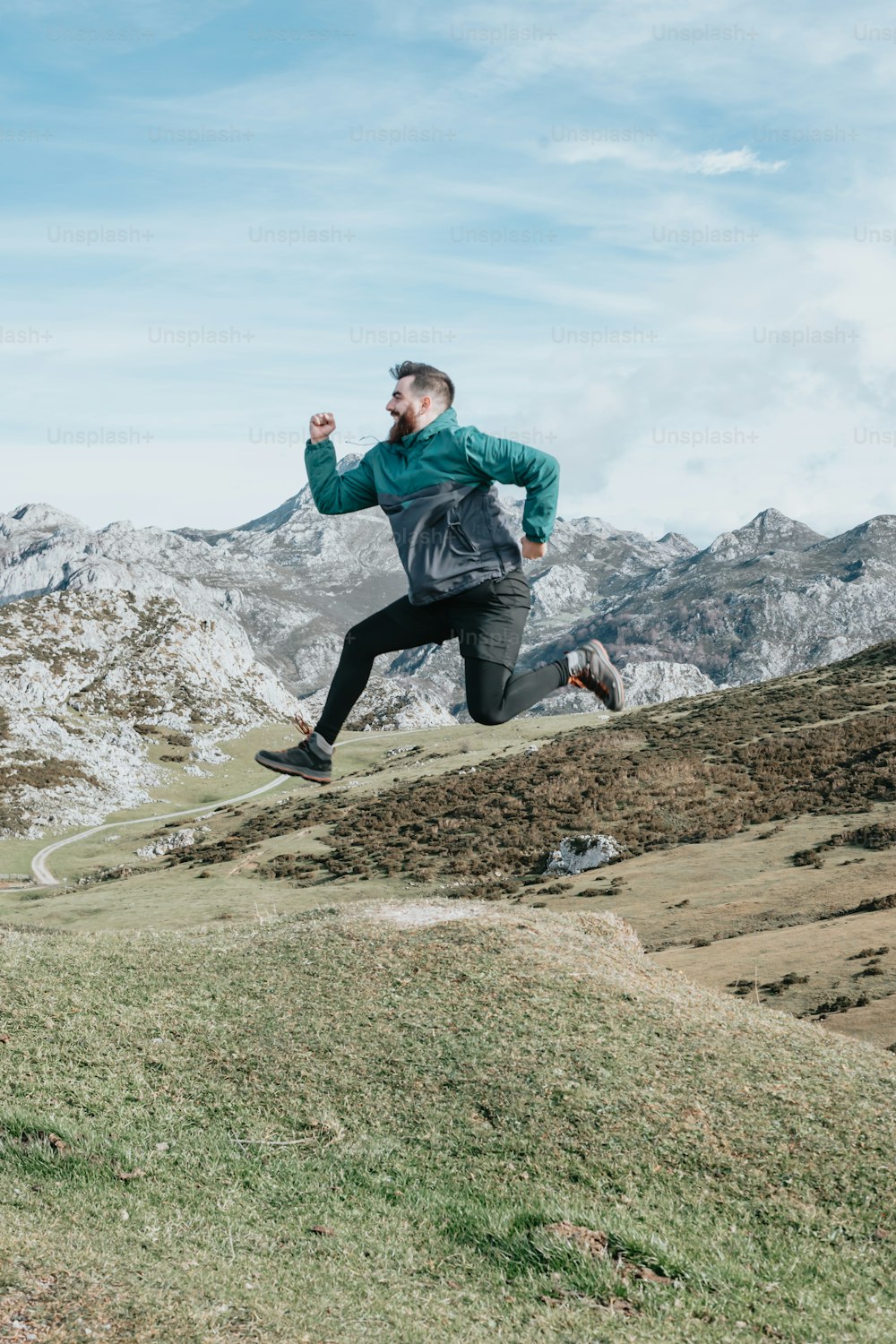 a man running up a hill with mountains in the background