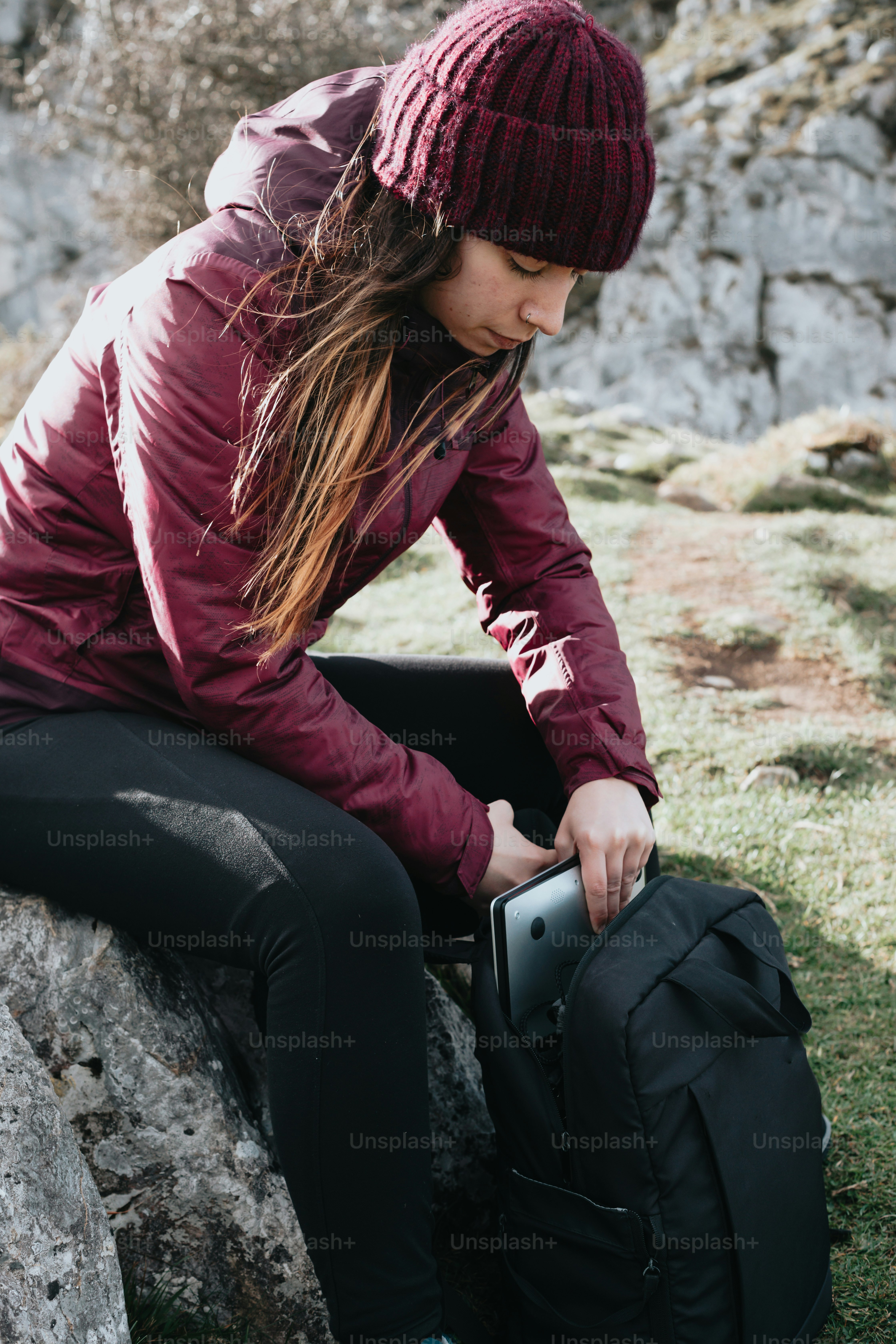 A woman sitting on a rock with a backpack photo – Mountains Image on ...